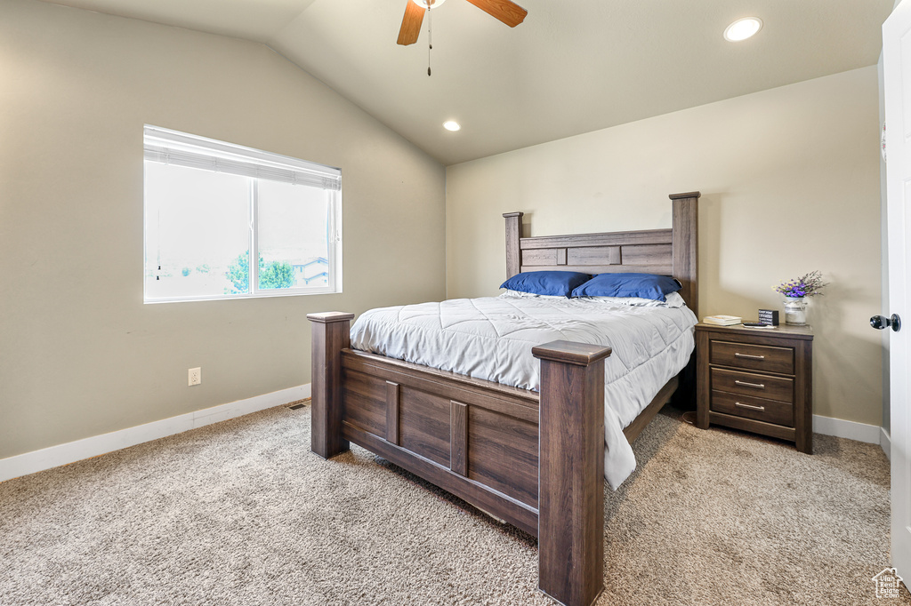 Bedroom with ceiling fan, vaulted ceiling, and light colored carpet