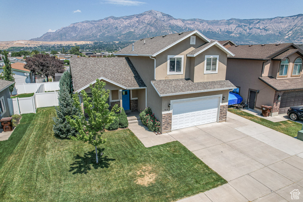 View of front of property with a mountain view, a garage, and a front lawn