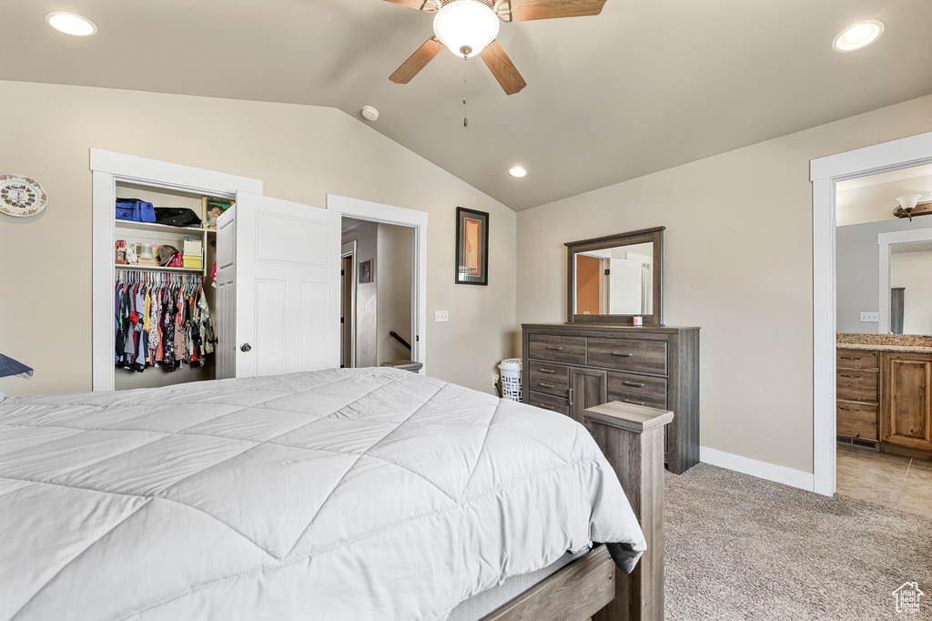 Carpeted bedroom featuring a closet, connected bathroom, ceiling fan, and vaulted ceiling