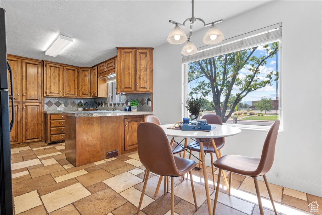 Kitchen featuring light tile patterned flooring, backsplash, pendant lighting, and a healthy amount of sunlight