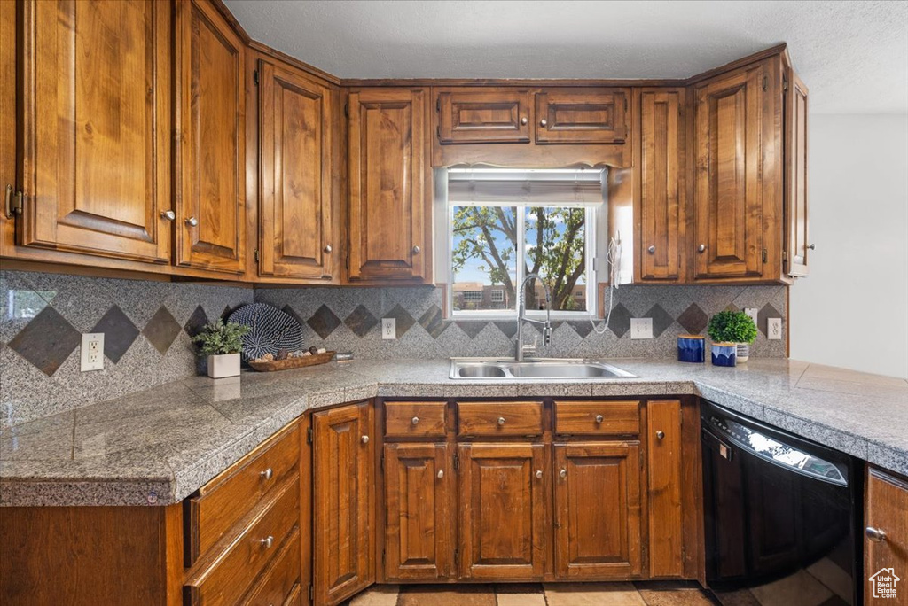 Kitchen with decorative backsplash, light tile patterned floors, black dishwasher, and sink