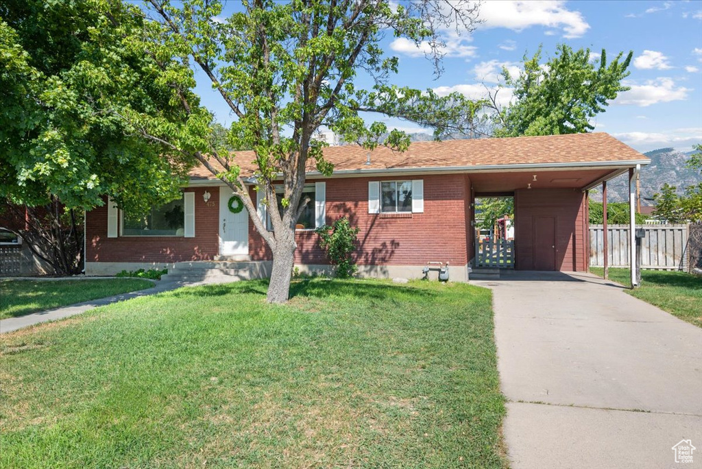 Ranch-style home featuring a front lawn and a carport