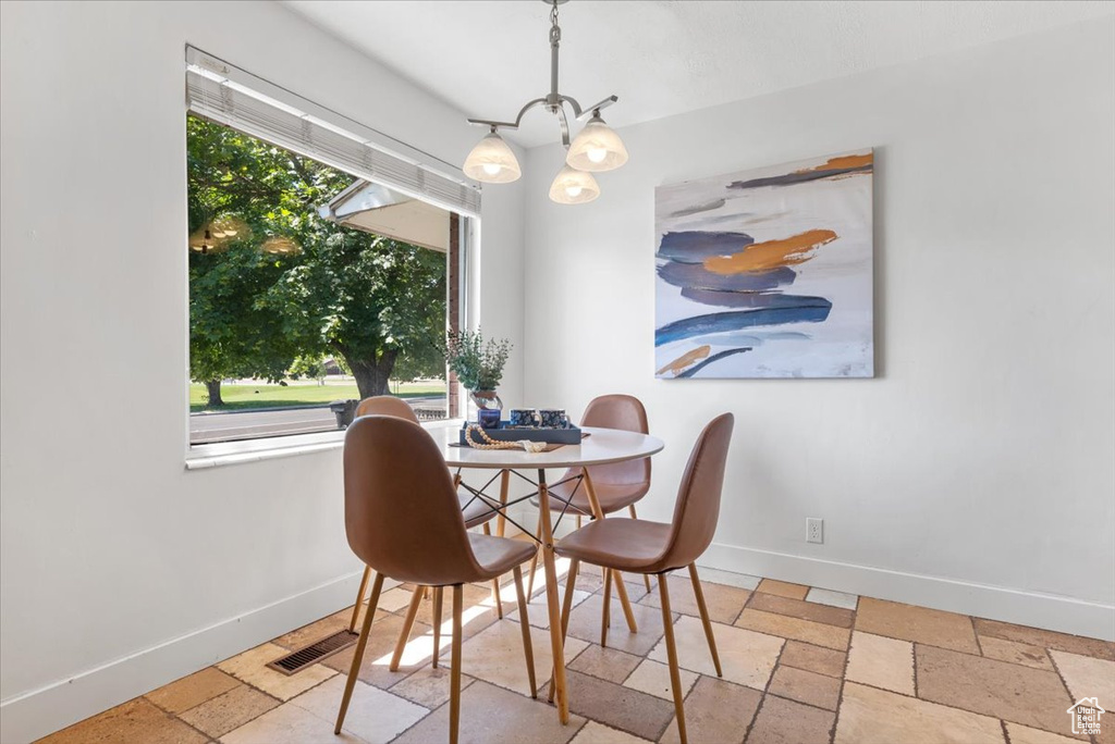 Dining space featuring light tile patterned flooring, a wealth of natural light, and a chandelier