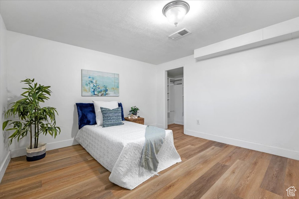 Bedroom with a spacious closet, hardwood / wood-style flooring, and a closet