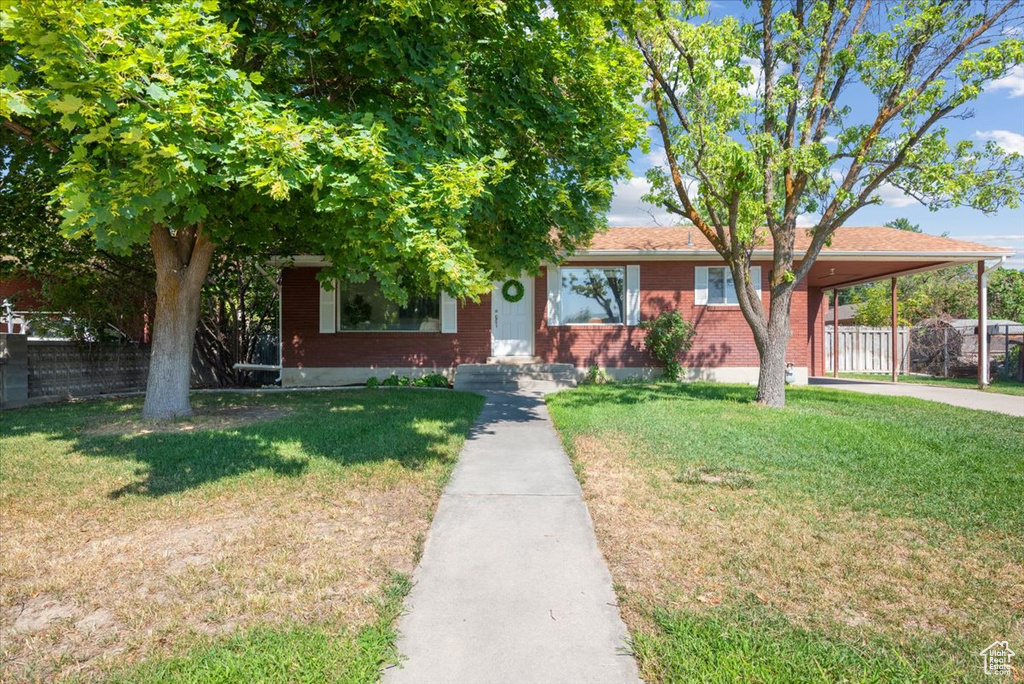 View of front facade with a front yard and a carport