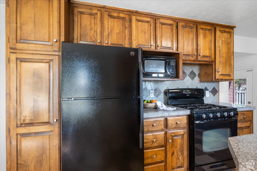 Kitchen with decorative backsplash and black appliances