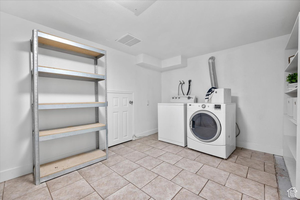 Laundry area with light tile patterned flooring and washing machine and dryer