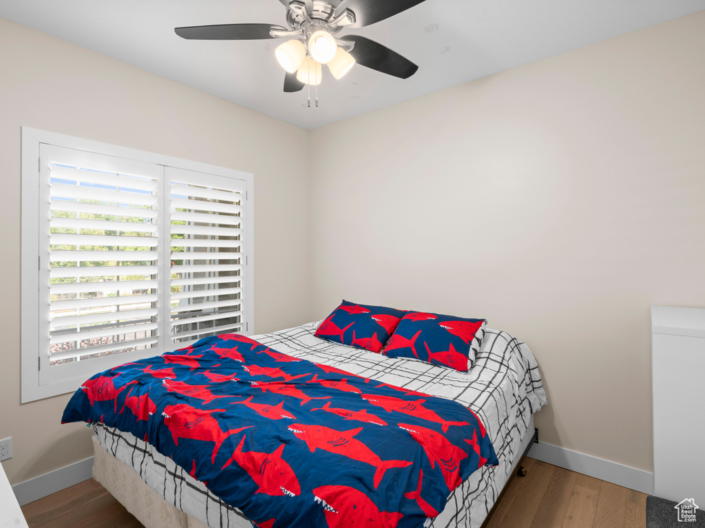 Bedroom with multiple windows, ceiling fan, and hardwood / wood-style floors