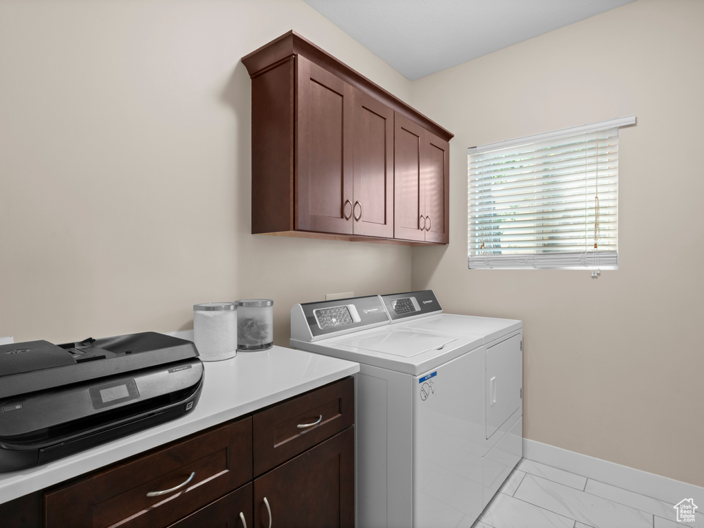 Clothes washing area with cabinets, independent washer and dryer, and light tile patterned floors