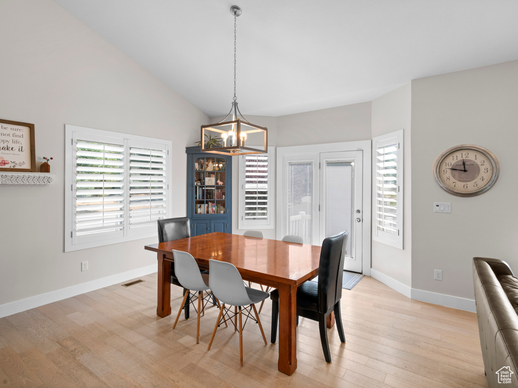 Dining room with light hardwood / wood-style floors, high vaulted ceiling, and a chandelier