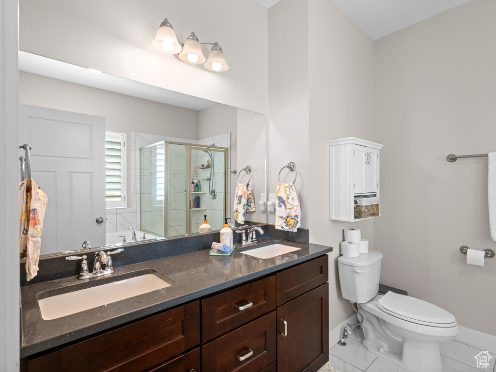 Bathroom with dual vanity, toilet, and tile patterned floors