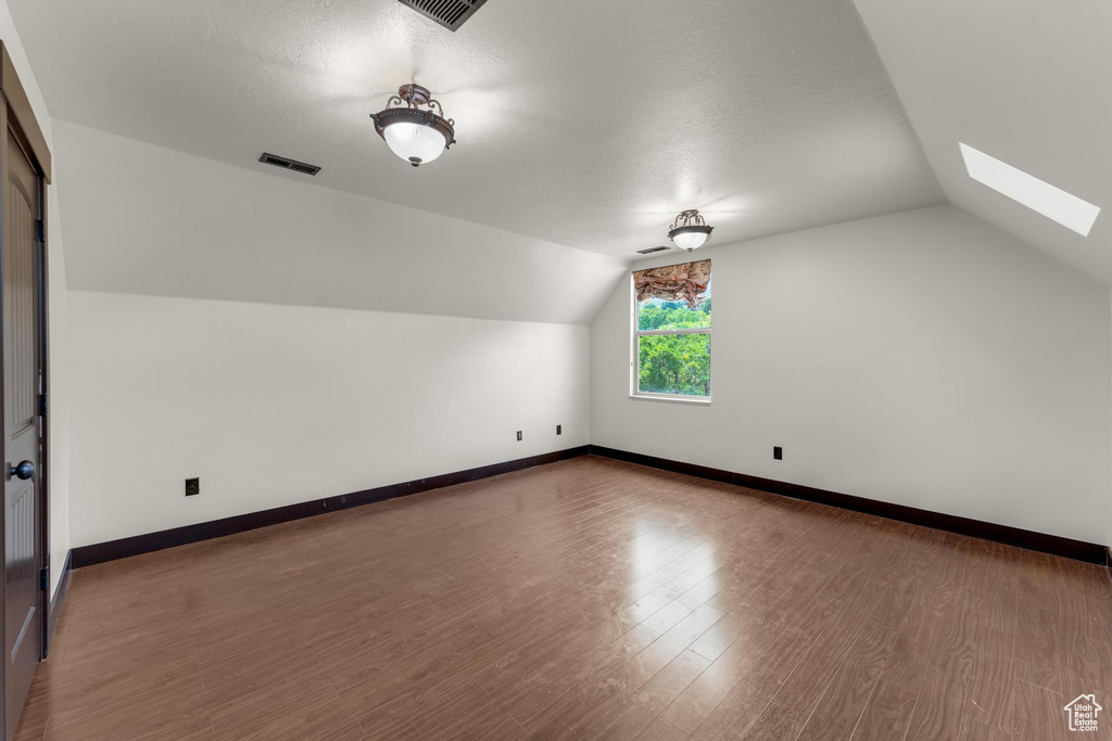 Additional living space featuring lofted ceiling with skylight and hardwood / wood-style flooring