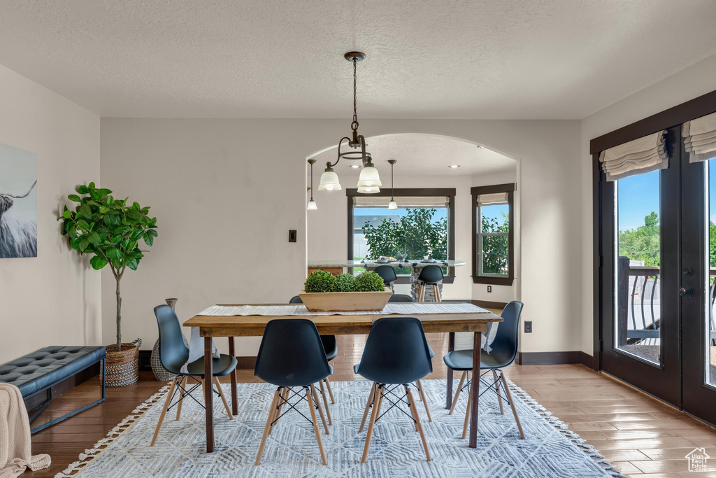 Dining space featuring light wood-type flooring, french doors, and a textured ceiling