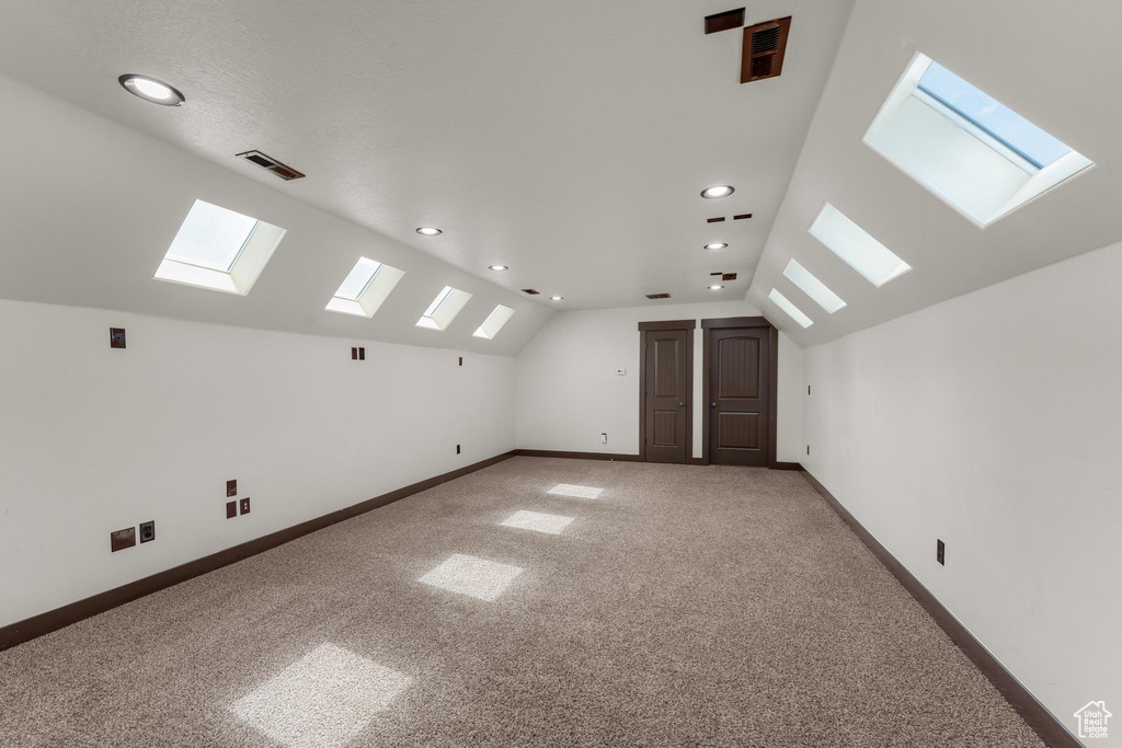 Bonus room with carpet floors and vaulted ceiling with skylight