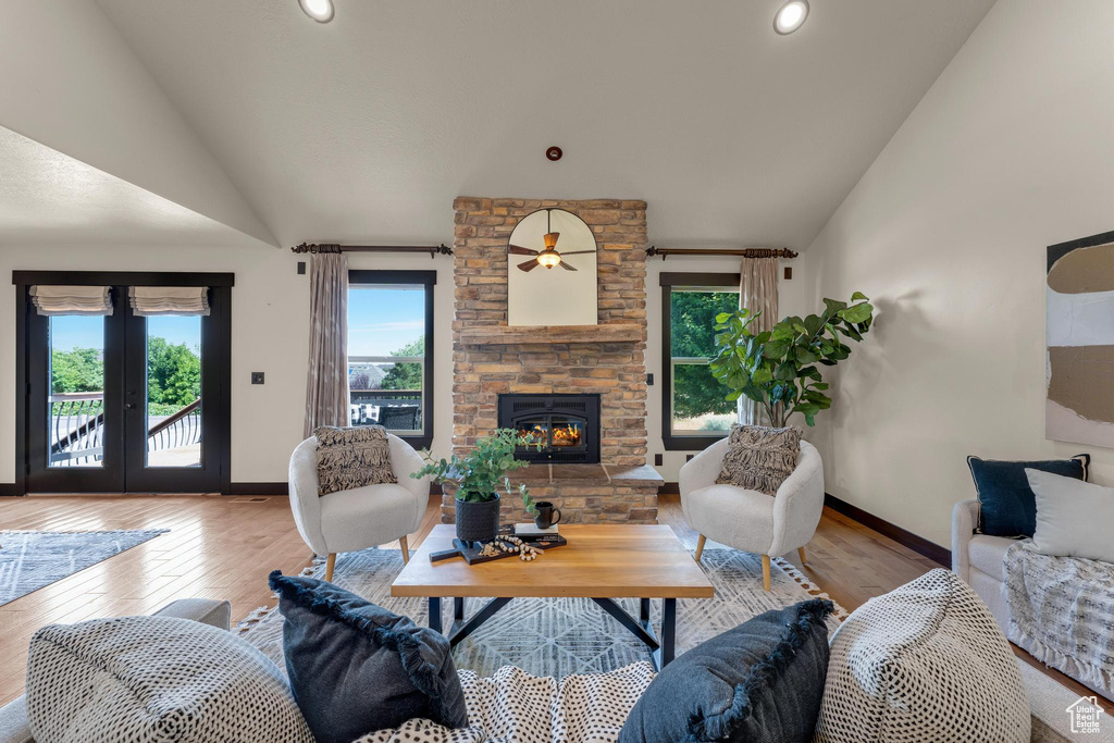 Living room with a fireplace, wood-type flooring, lofted ceiling, and french doors