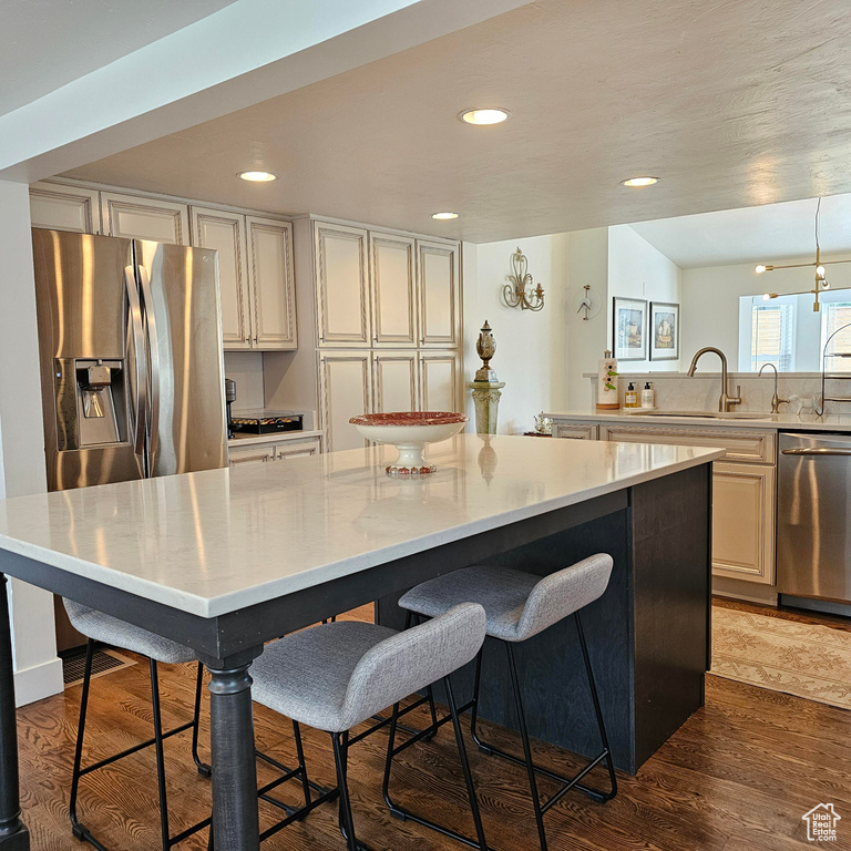 Kitchen featuring stainless steel appliances, a kitchen bar, a kitchen island, and dark hardwood / wood-style floors