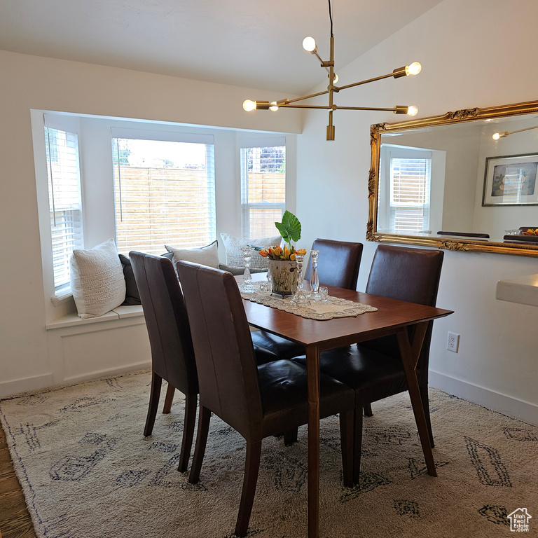 Dining room with a notable chandelier, a wealth of natural light, and vaulted ceiling