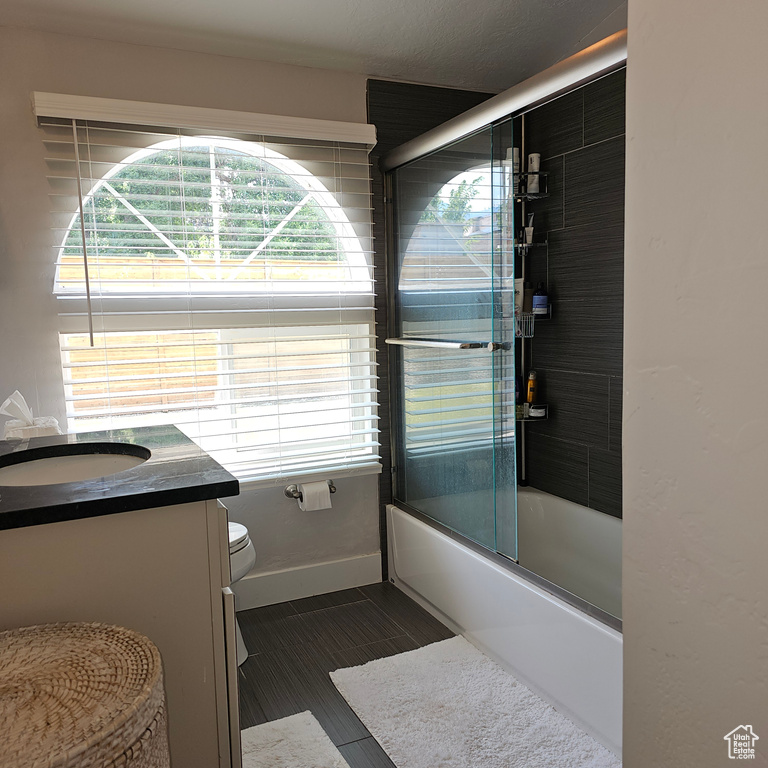 Full bathroom with vanity, toilet, tile patterned floors, and enclosed tub / shower combo