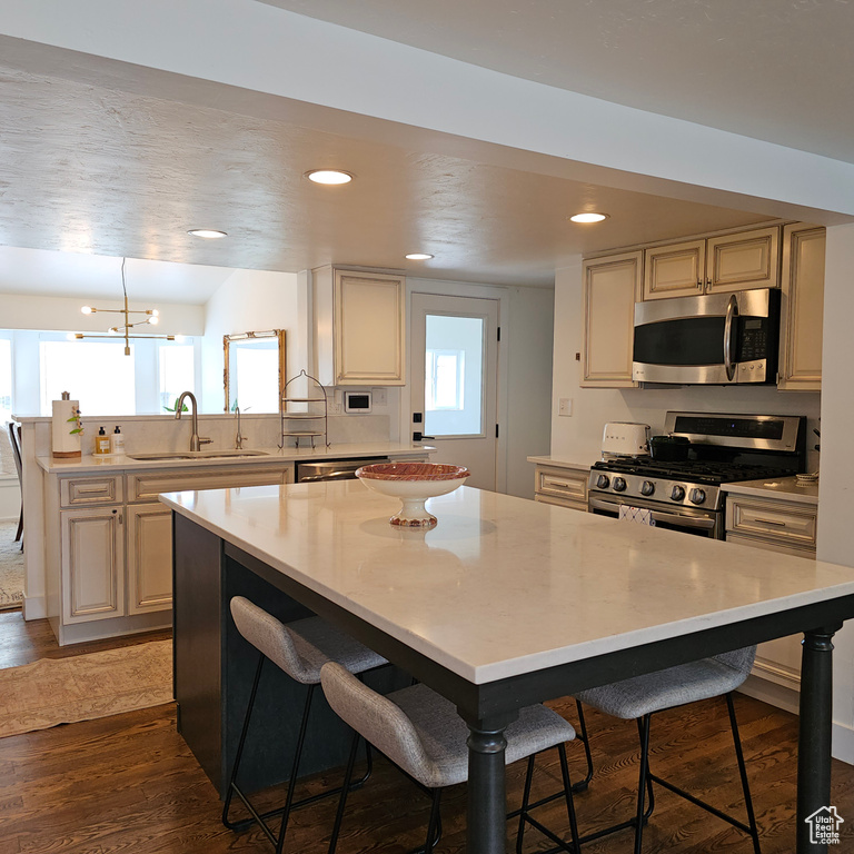 Kitchen featuring a kitchen bar, sink, stainless steel appliances, and hardwood / wood-style floors