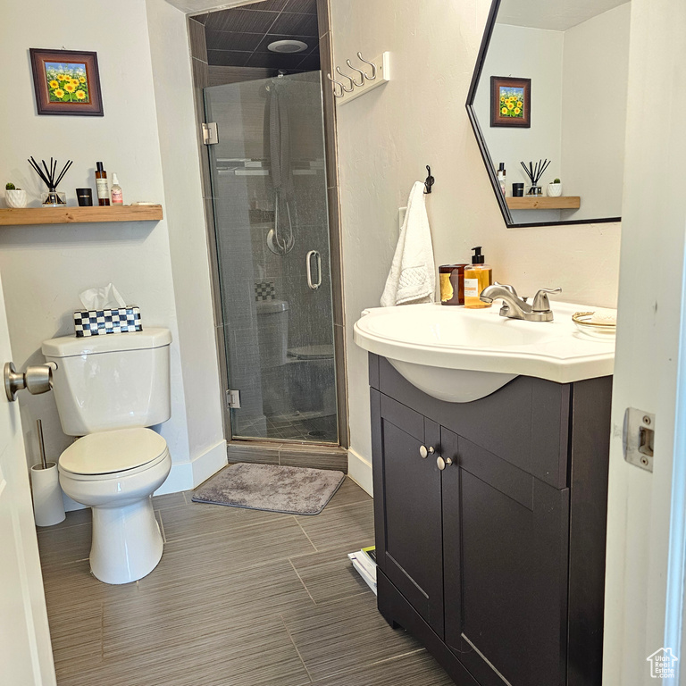 Bathroom featuring vanity, toilet, walk in shower, and tile patterned floors