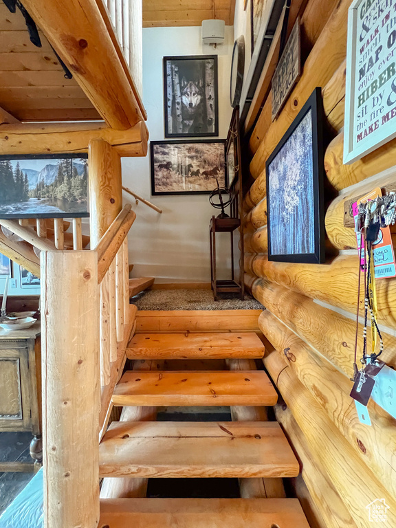 Staircase with wooden ceiling and rustic walls