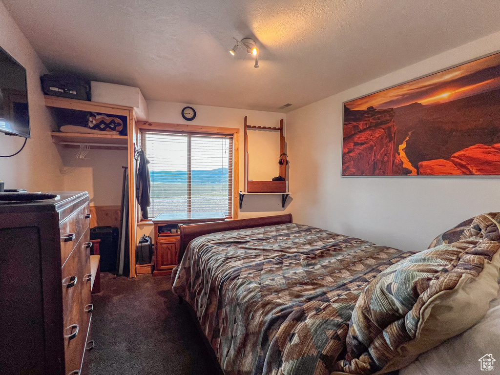 Bedroom featuring dark colored carpet and a textured ceiling