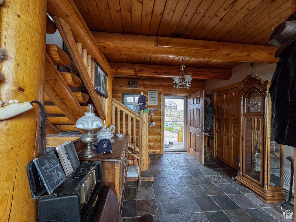 Interior space featuring wooden ceiling, dark tile patterned flooring, beam ceiling, and rustic walls