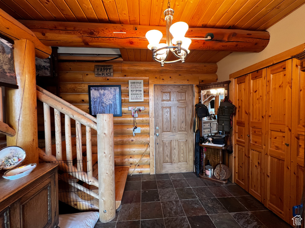 Tiled entryway with a chandelier, beamed ceiling, wood ceiling, and log walls