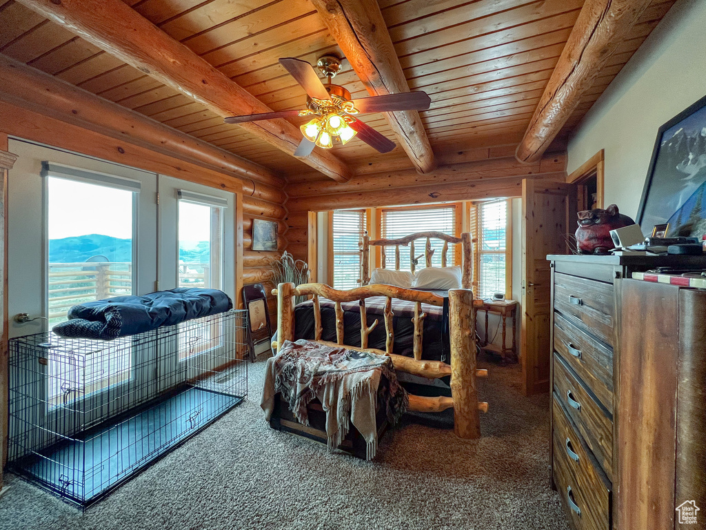 Carpeted bedroom featuring a mountain view, beamed ceiling, multiple windows, and wood ceiling