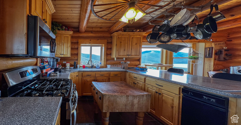 Kitchen with stainless steel appliances, a center island, dark tile patterned flooring, and rustic walls