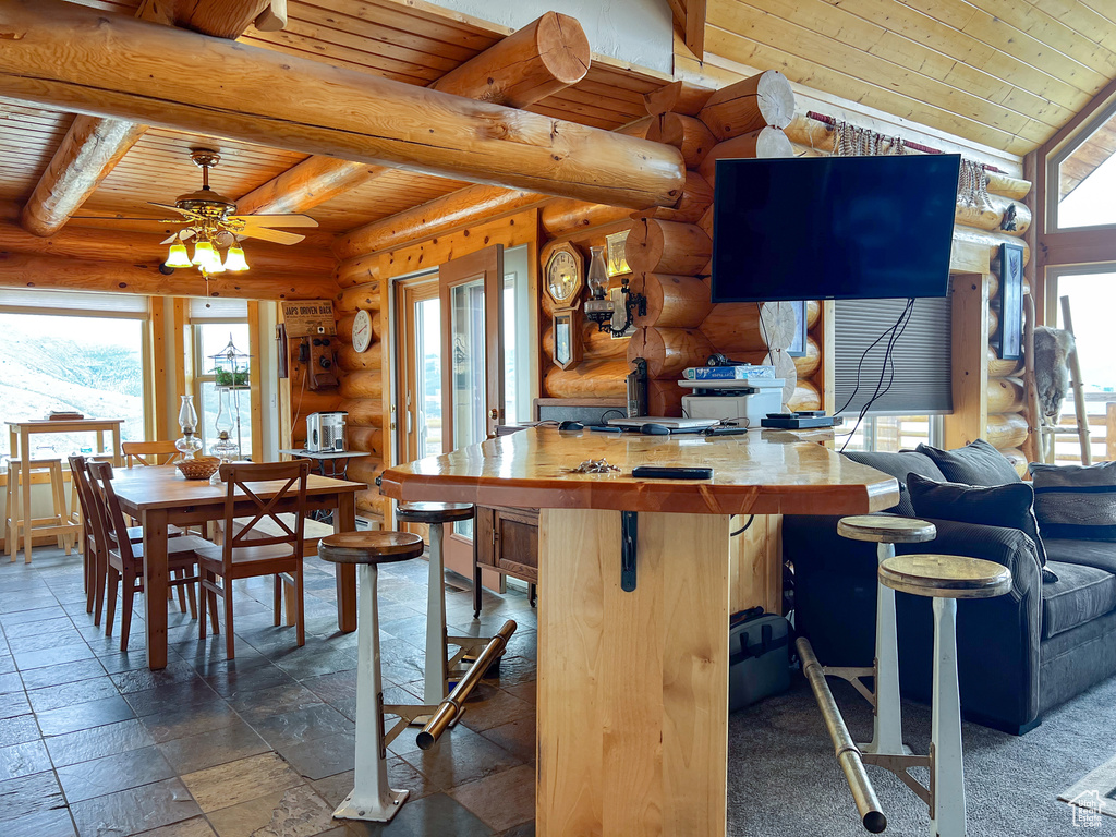 Kitchen featuring tile patterned flooring, wood ceiling, a wealth of natural light, and log walls