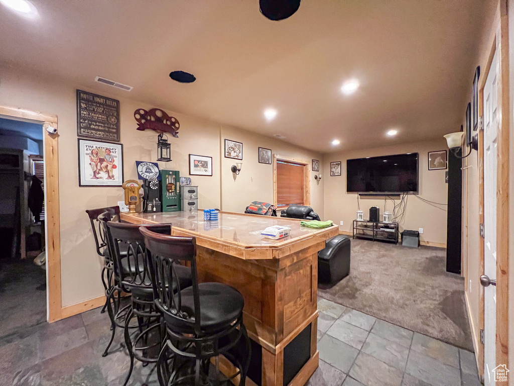 Interior space with carpet floors, a breakfast bar area, and kitchen peninsula