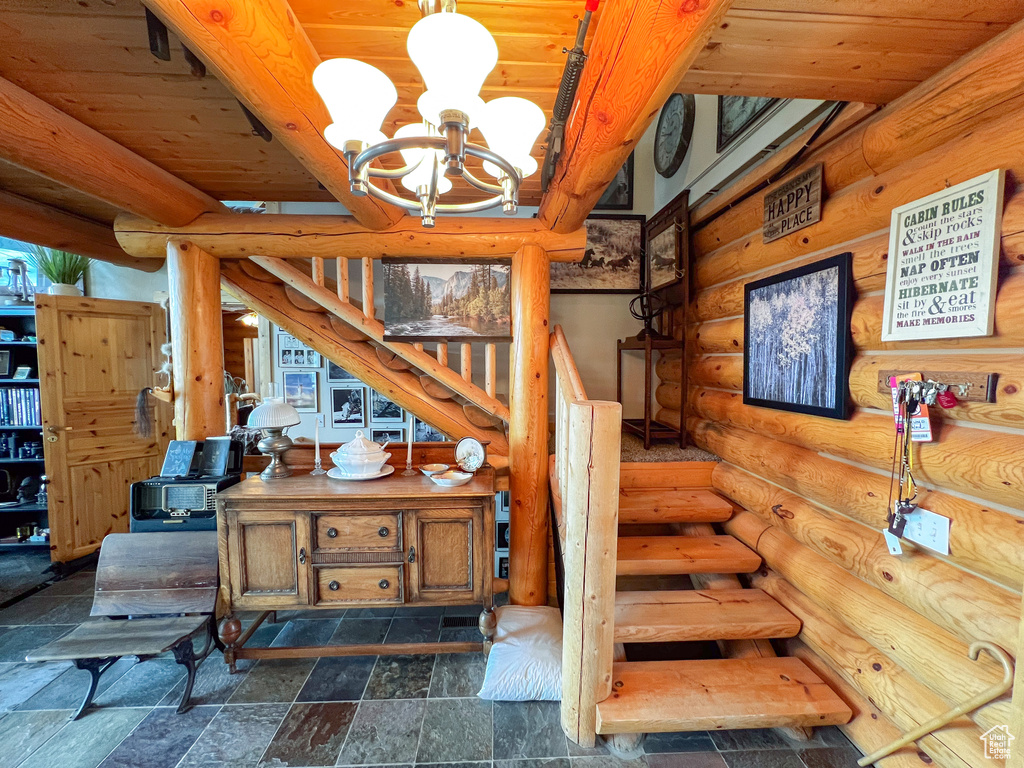 Stairs featuring a chandelier, rustic walls, beam ceiling, dark tile patterned flooring, and wood ceiling