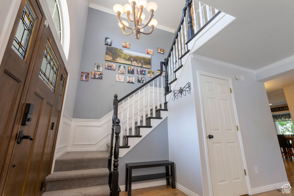 Foyer entrance featuring an inviting chandelier, wood-type flooring, and ornamental molding