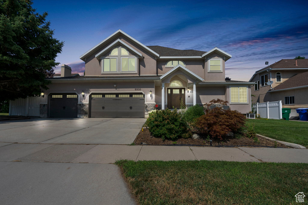 View of front facade with a garage and a lawn