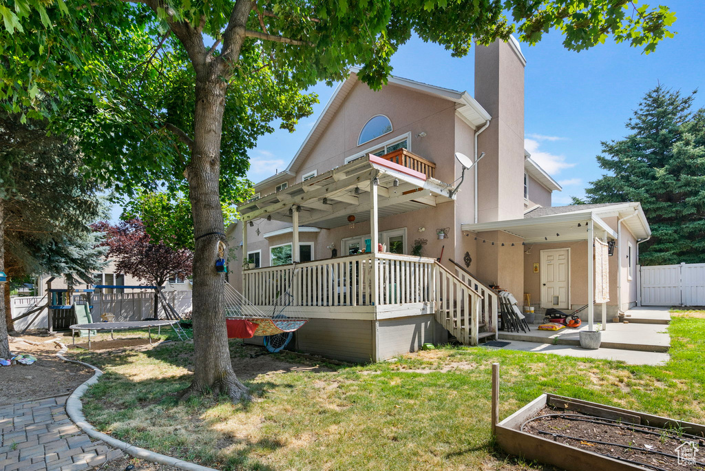 Back of house with a wooden deck, a yard, and a pergola