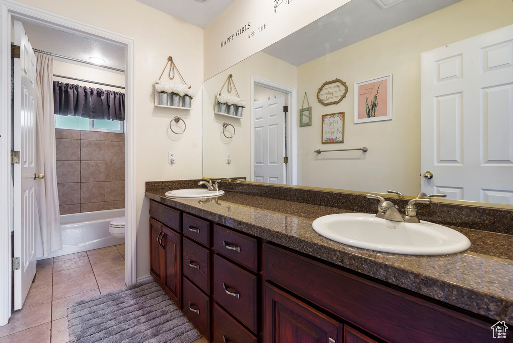 Full bathroom featuring shower / tub combo with curtain, double vanity, toilet, and tile patterned floors