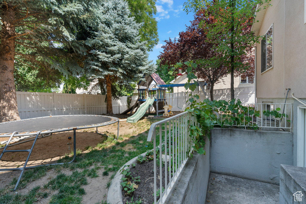 View of yard featuring a playground and a trampoline