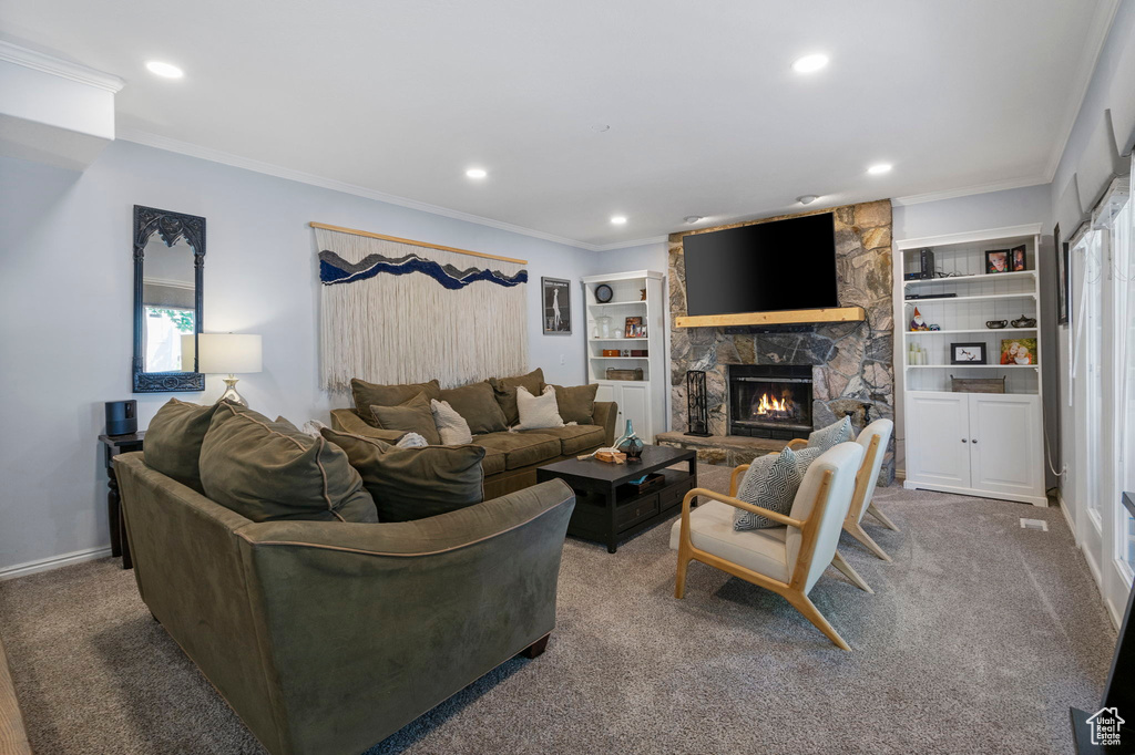 Living room featuring carpet, a stone fireplace, built in shelves, and a wealth of natural light