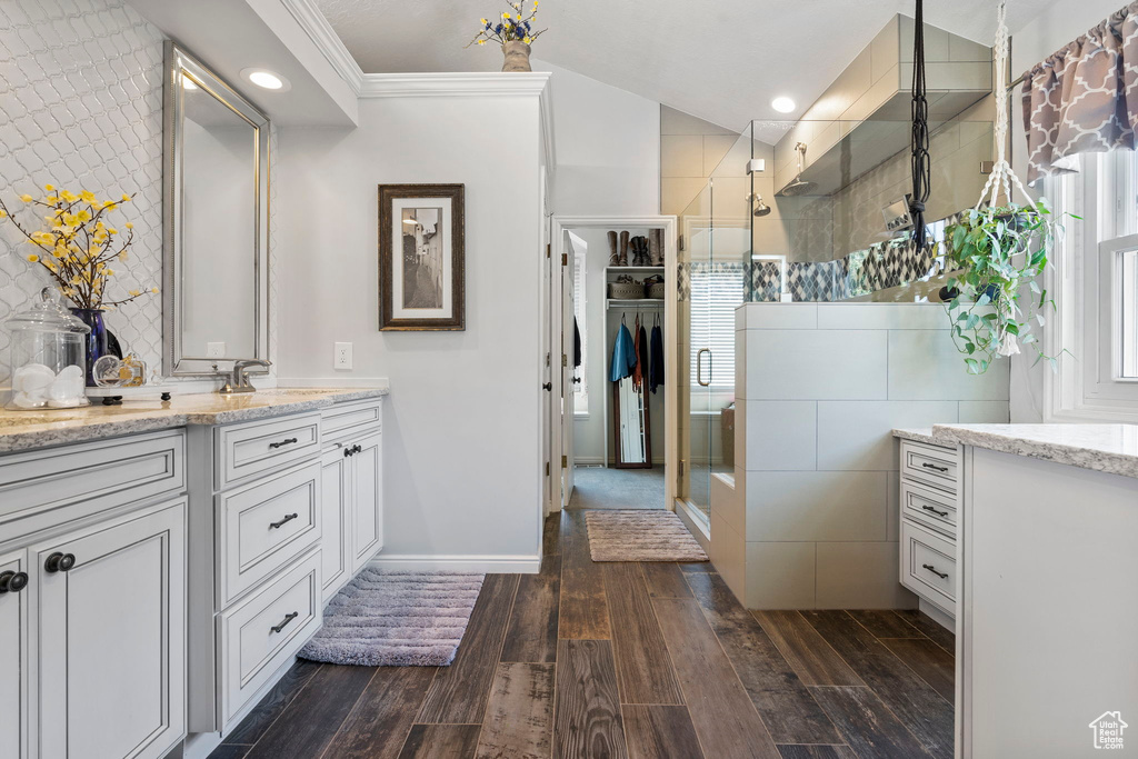 Bathroom featuring tile walls, wood-type flooring, crown molding, and vanity