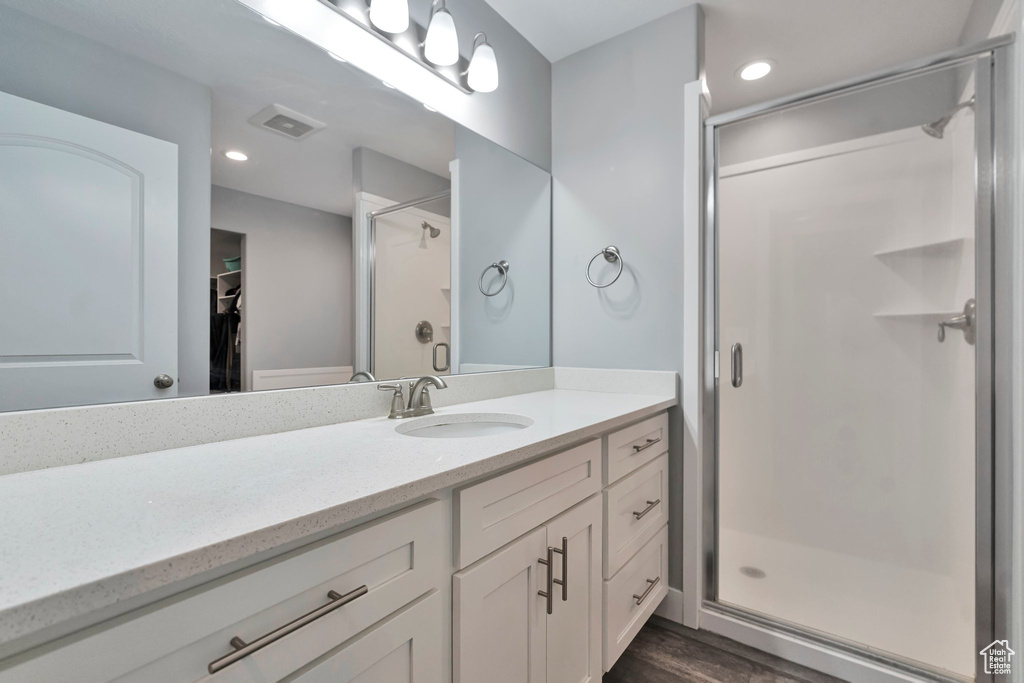 Bathroom with a shower with shower door, vanity, and hardwood / wood-style floors