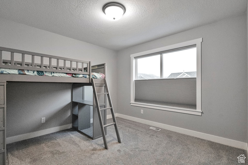 Unfurnished bedroom with a textured ceiling and carpet flooring