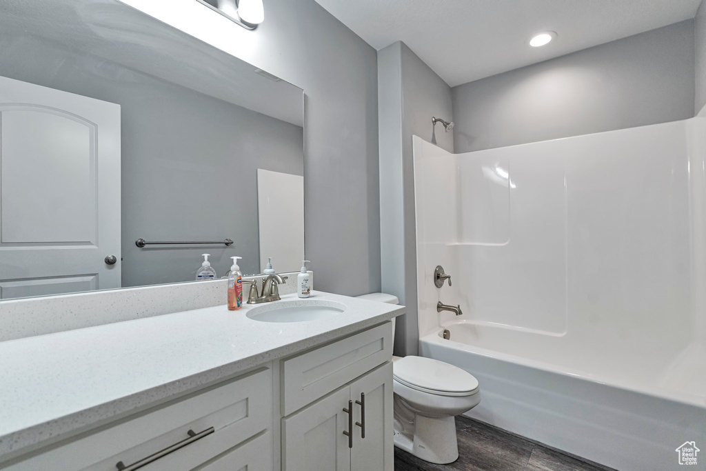 Full bathroom with vanity, bathtub / shower combination, toilet, and hardwood / wood-style floors