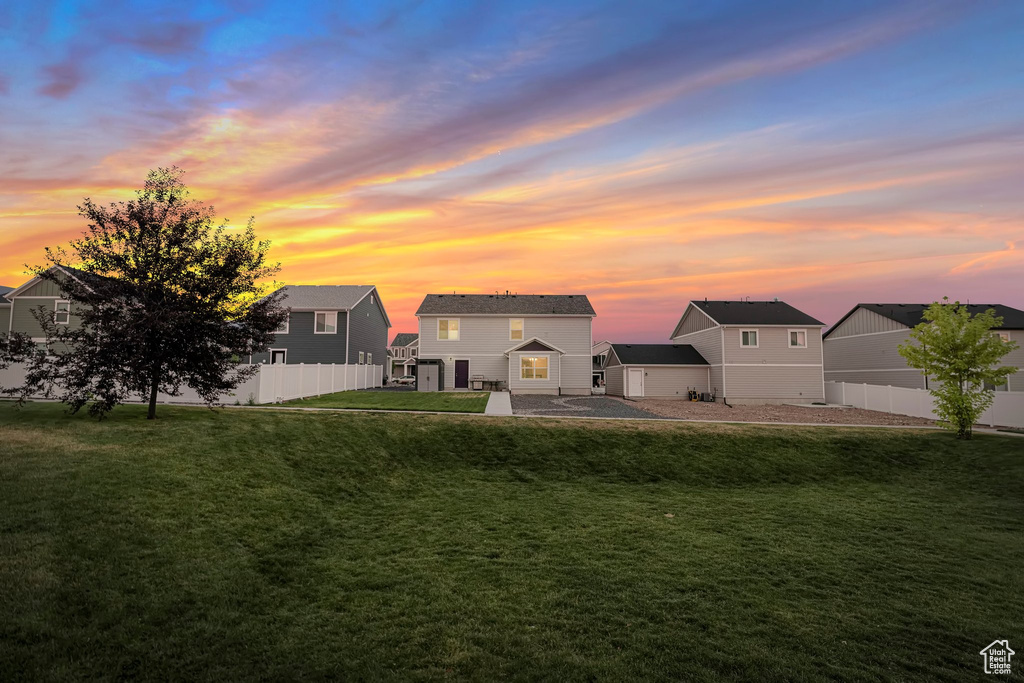 Back house at dusk featuring a patio and a yard