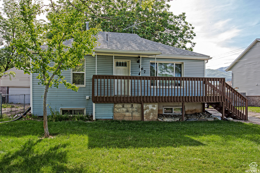 Rear view of property featuring a wooden deck and a yard