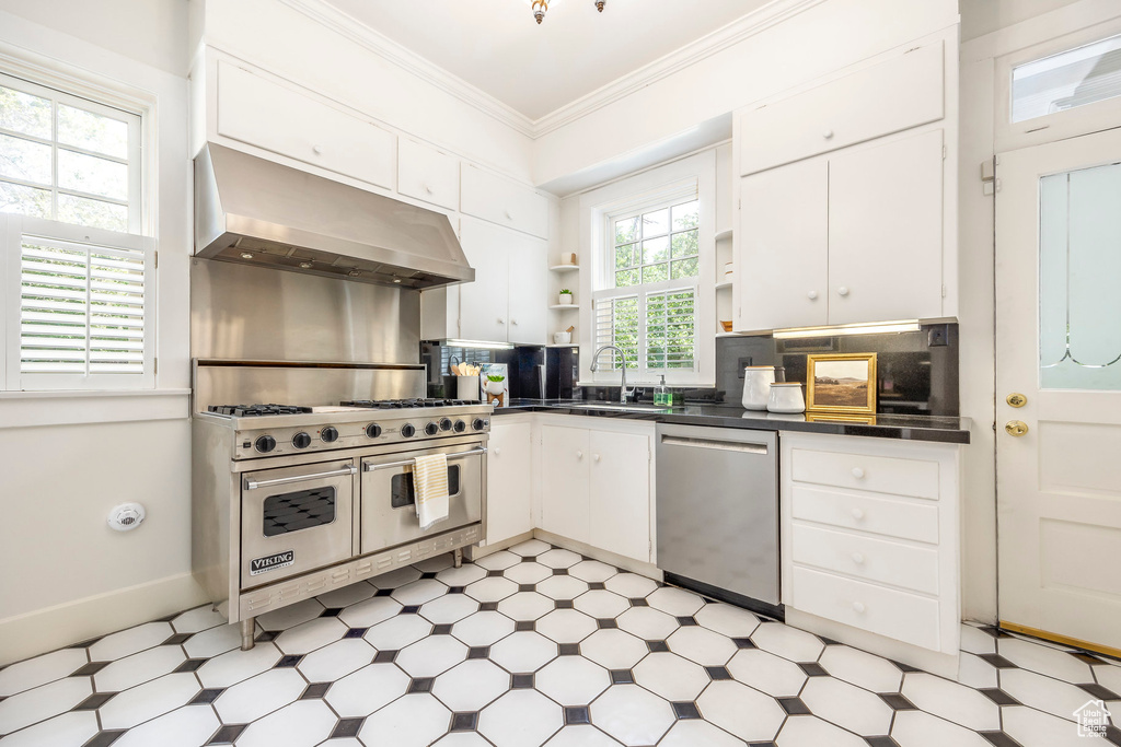 Kitchen featuring light tile patterned flooring, tasteful backsplash, extractor fan, stainless steel appliances, and sink