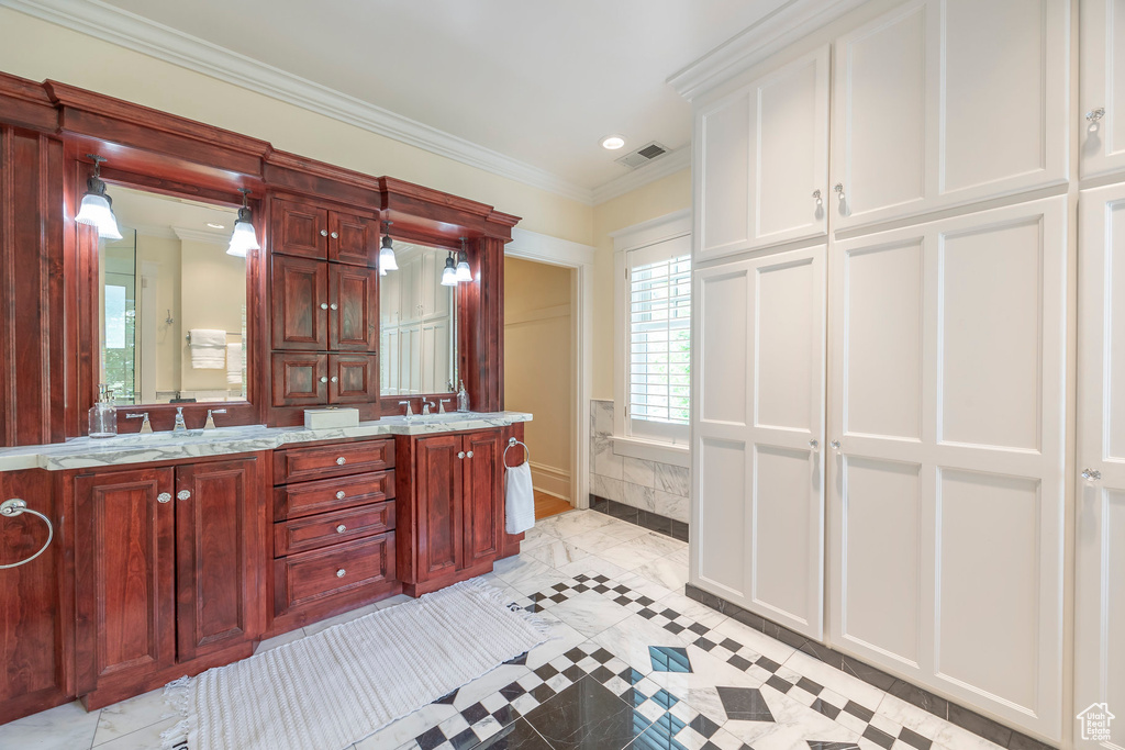 Bathroom with tile patterned floors, ornamental molding, and dual bowl vanity