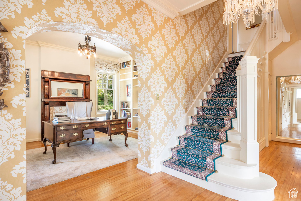 Stairway with wood-type flooring, ornamental molding, and a notable chandelier