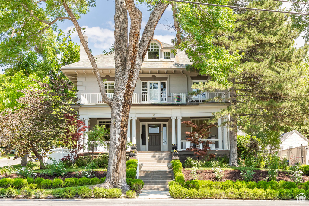 View of front of house with covered porch and a balcony