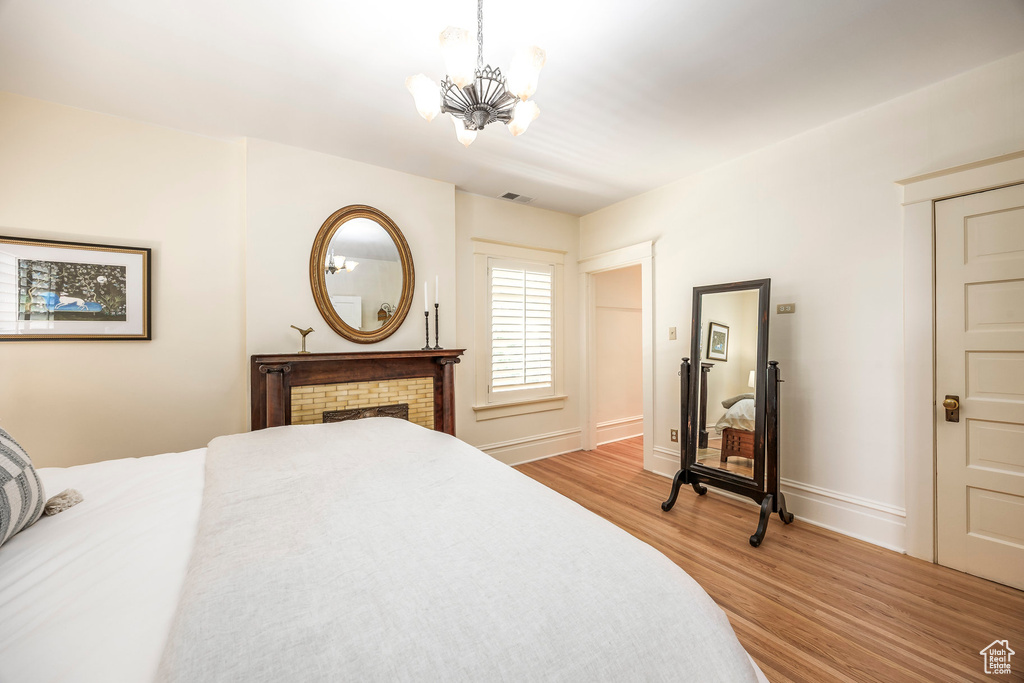 Bedroom featuring a fireplace, a notable chandelier, and hardwood / wood-style floors